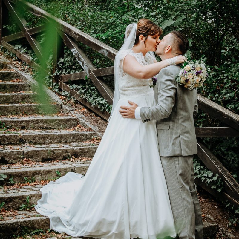 Hochzeitsbild von Brautpaar küsst sich auf romantischer Treppe im Stadtpark Bernau