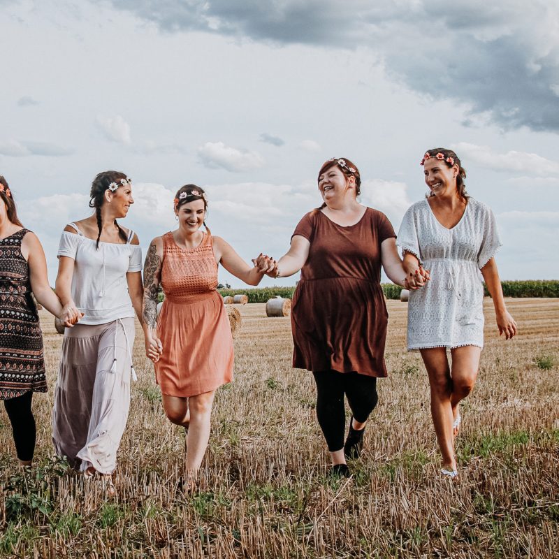 5 lachende Freundinnen rennen Hand in Hand übers Feld in Oberhavel