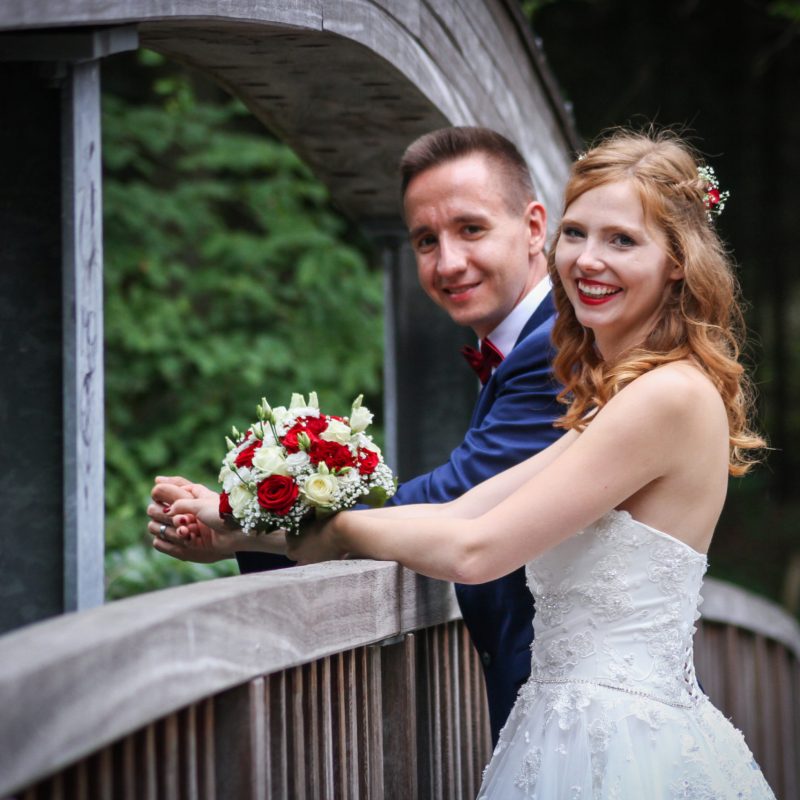 Hochzeitsbild von Brautpaar mit Brautstrauss auf einer Holzbrücke in Hohen Neuendorf