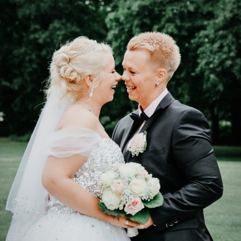 Hochzeitsbild von glücklich lächelndem Brautpaar auf einer Wiese im Schlosspark Oranienburg