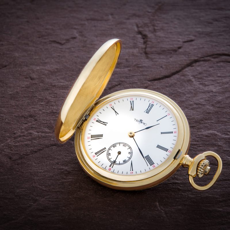 Produktfoto einer goldenen Tempic Taschenuhr auf Schieferplatte