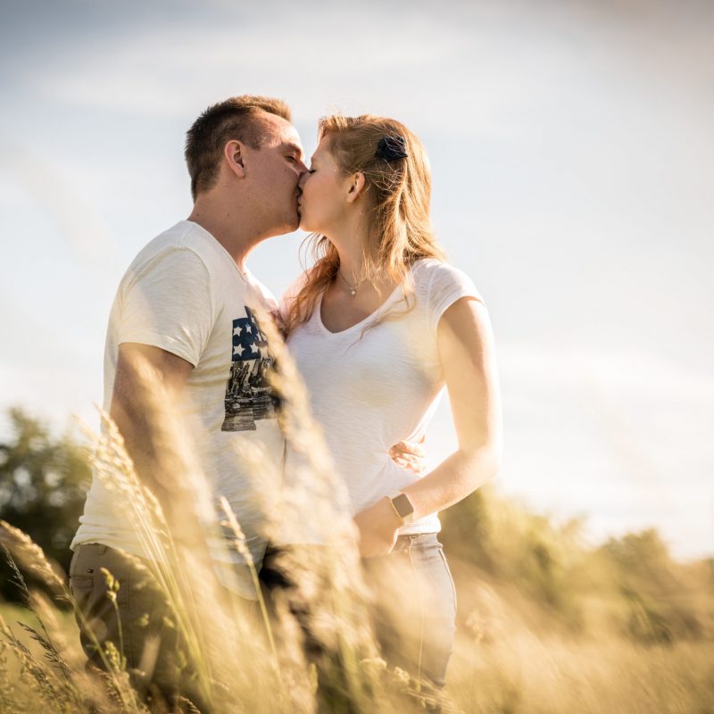 Liebespaar küsst sich bei Sonnenuntergang auf einem Feld in Ofenstadt Velten